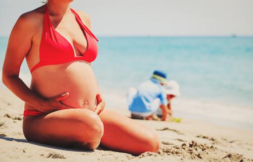 Une femme enceinte assise sur le sable à la plage