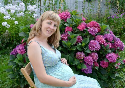 Une femme enceinte est assise dans son jardin