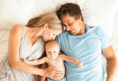 Un couple de parents avec leur bébé dans leur lit