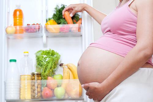 Une femme enceinte ouvre son frigo