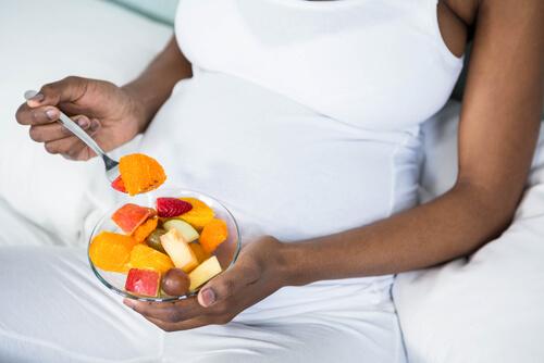 Une femme enceinte mange une salade de fruits