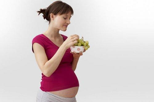 Une femme enceinte mange du raisin