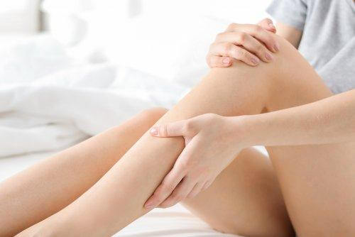 Une femme se masse la jambe et le genou