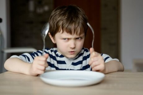 Un enfant va manger avec des couverts