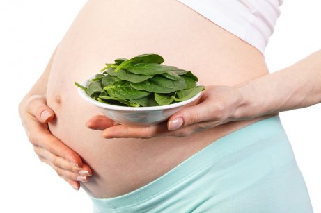 Une femme enceinte avec une assiette d'épinards