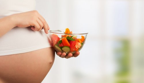 Le ventre d'une femme enceinte avec une salade de légume. 