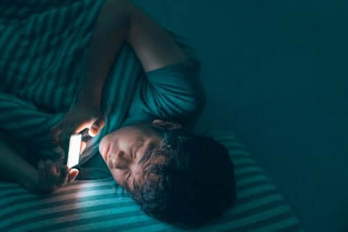 Un adolescent qui regarde son téléphone au lit.
