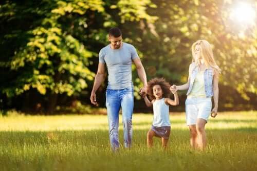 Petite fille qui tient la main de ses parents