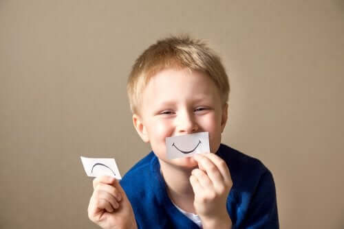 Enfant avec un sourire en papier devant la bouche