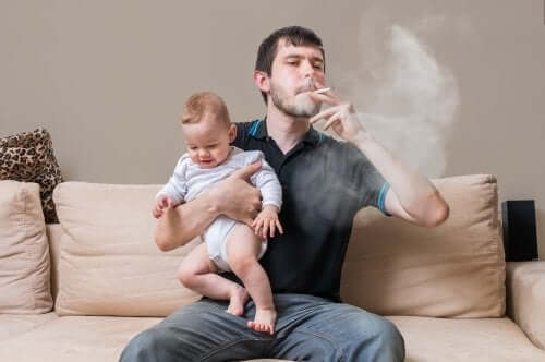 père fumant une cigarette avec son bébé