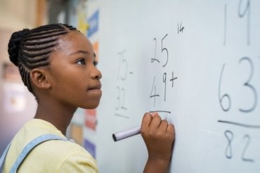 enfant démontrant son intelligence mathématique au tableau