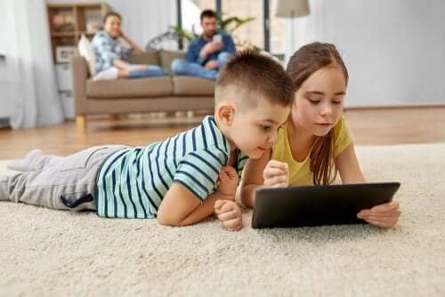 enfants devant leur tablette dans le salon avec leurs parents