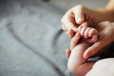 main de bébé attrapant le doigt de son père