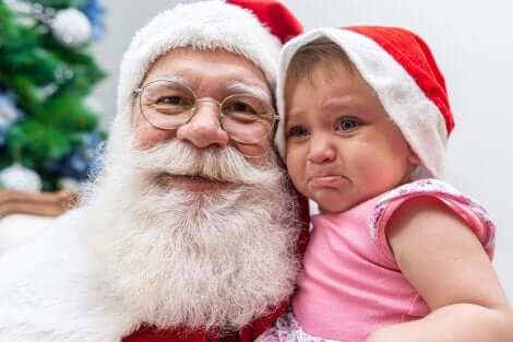 Un bébé qui pleure dans les bras du Père Noël. 