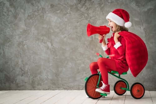 Une fillette sur un tricycle avec un chapeau de Noël.