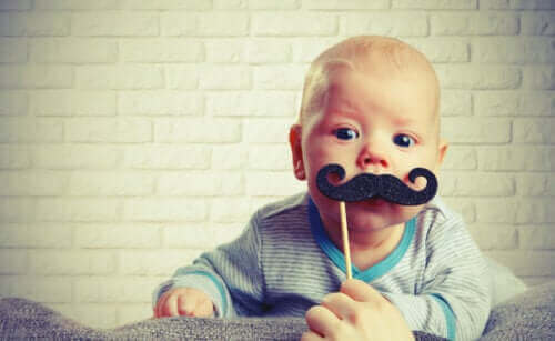 bébé tenant une fausse moustache