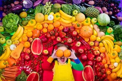Une jeune fille entourée de fruits de toutes les couleurs.
