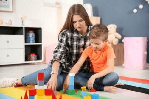 Un enfant autiste joue aux cubes avec sa maman