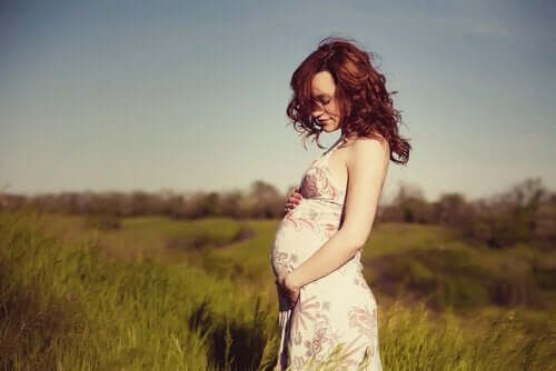Une femme enceinte dans un champ en été.