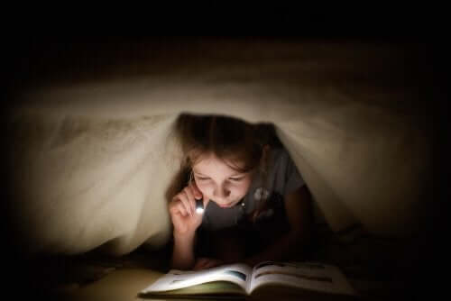 Un enfant qui lit sous sa couette.