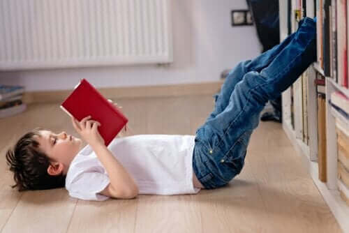 enfant lisant un livre assis par terre pendant le confinement