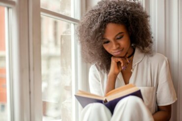 femme jeune lisant un livre à la fenêtre