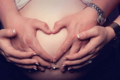 mains formant un coeur sur le ventre d'une femme enceinte