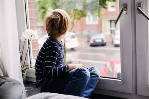 Un enfant souffrant de trouble de l'autisme qui regarde par la fenêtre.