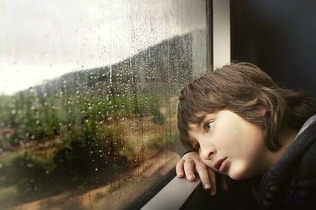 Un enfant fatigué regardant par la fenêtre.
