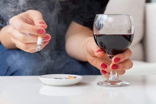 Une femme buvant un verre de vin et fumant