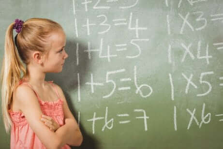 Une jeune fille devant un tableau noir avec des opérations mathématiques.