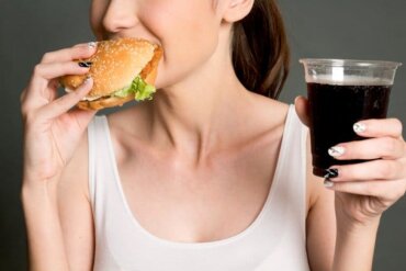 Une femme mangeant un burger et buvant du coca