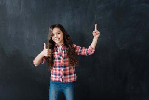 Une jeune fille souriant devant un tableau noir.