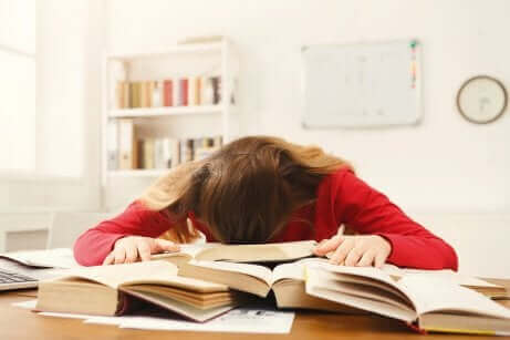 Une fille endormie sur des livres.