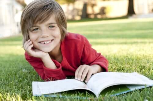enfant lisant un livre dans l'herbe