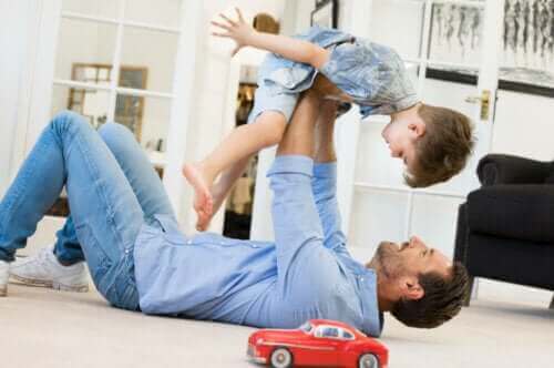 Un père jouant avec son fils avec une voiture en jouet dans le salon de la maison.