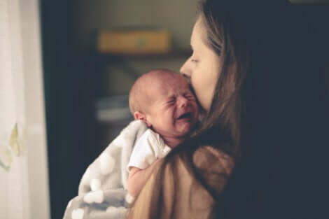 Un bébé qui pleure dans les bras de sa mère.