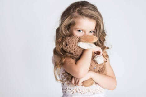 Une fille se cachant derrière sa peluche.