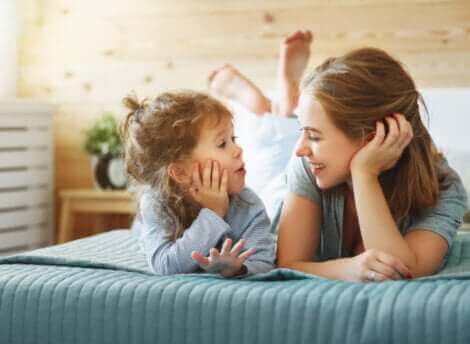 Une mère et sa fille discutant sur un lit.