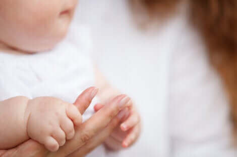 Un bébé tenant la main de sa mère.