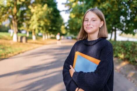 Une adolescente qui sourit avec des livres dans les bras. 