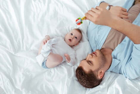 Un papa qui joue avec un hochet et son bébé. 