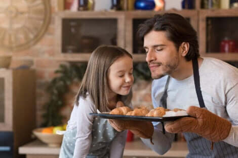 Un père et sa fille qui sentent des gâteaux sortant du four.
