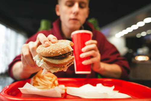 adolescent qui mange dans une restauration rapide ou fast-food