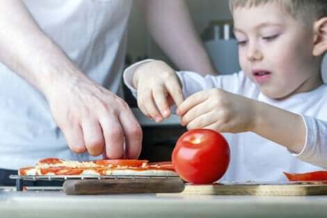 Un jeune enfant qui met des tomates sur une pizza. 