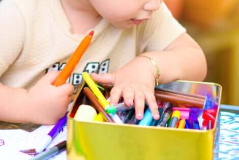 Un enfant qui fait un dessin avec des feutres.