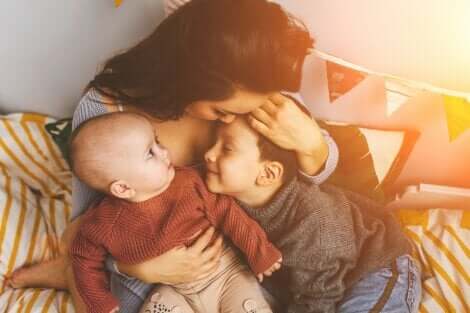 Une mère qui fait un câlin à ses deux enfants. 