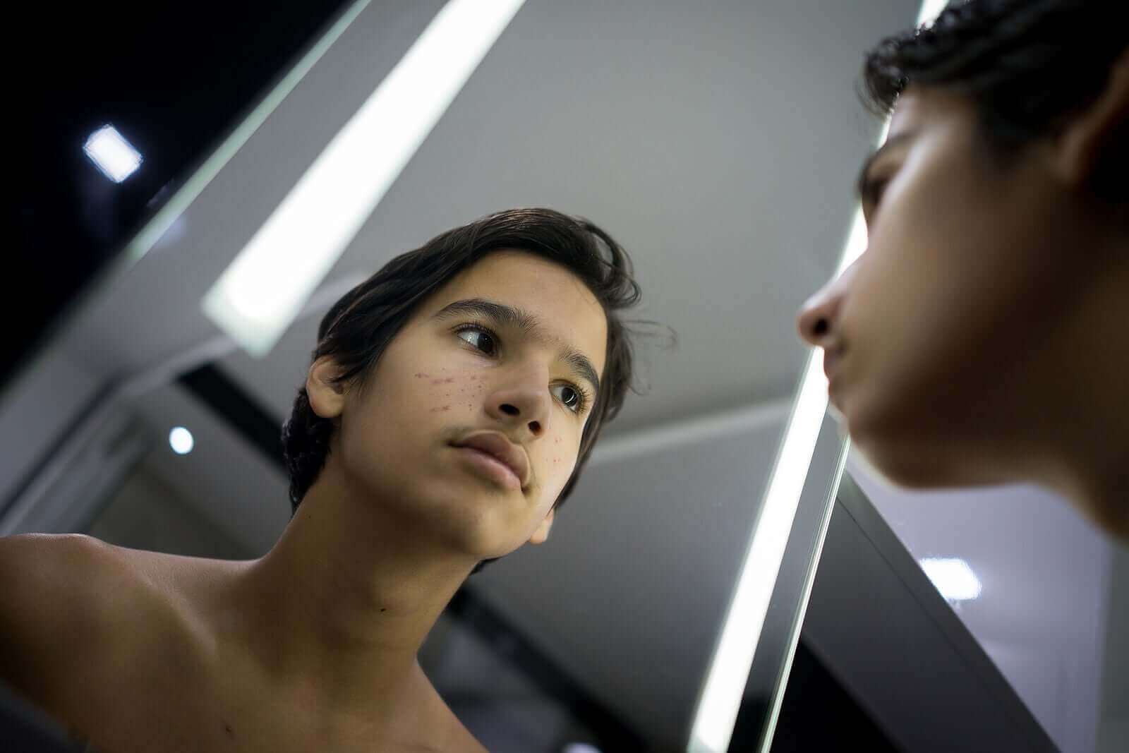 Un adolescent qui se regarde dans le miroir.