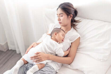Une maman qui dort avec son bébé sur ses genoux. 