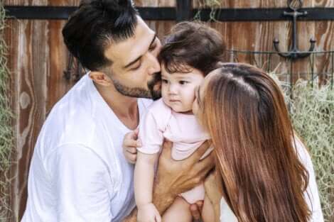 Deux parents qui font un câlin à leur enfant.